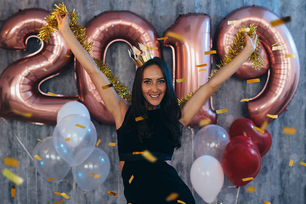 Frau in schwarzem Kleid und gelber Krone feiert Neujahr und hat Spaß - Foto, Bild