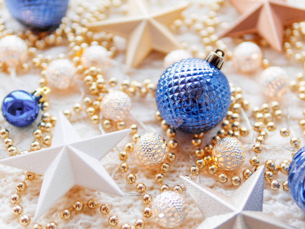 Christmas and New Year star decorations on white knitted background. Metal light bulbs with delicate pattern, golden beads and blue balls. - Valokuva, kuva