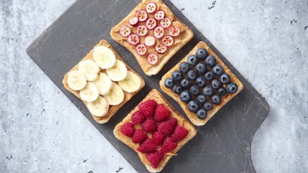 Wholegrain bread slices with peanut butter and various fruits - Footage, Video