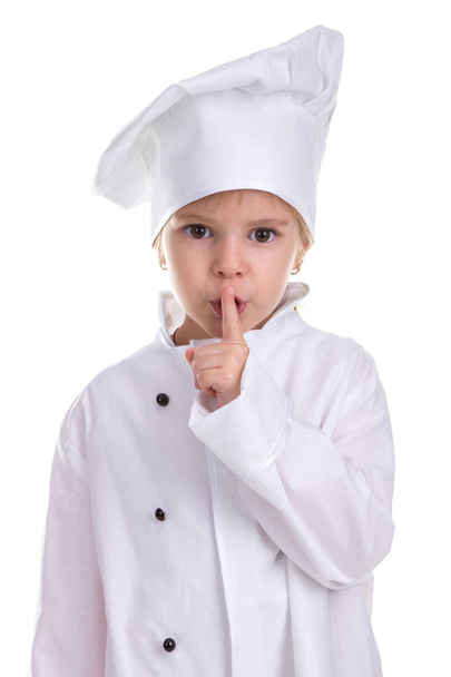 Smart Urocza dziewczyna kucharzem biały uniform izolowana na białym tle, przytrzymując palcem wskazującym w pobliżu usta. Hush znak. Obraz portret - Zdjęcie, obraz