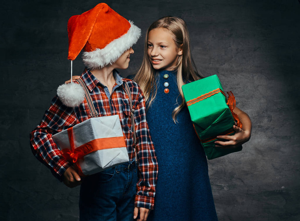 Ευτυχισμένο ζευγάρι λίγο αγκάλιασμα και κρατώντας κουτιά δώρα στο χρόνο Χριστουγέννων. - Φωτογραφία, εικόνα