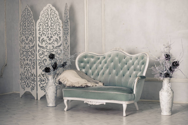 Interiér s vintage nábytek, retro krásná šedá pohovka. Bílá obývací interiér. Velké starožitné podlahové vázy s dekorativní květy. Šedá pohovka polštáře a deky - Fotografie, Obrázek