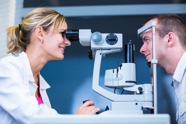 Optometry concept - handsome young man having her eyes examined - Foto, Imagen