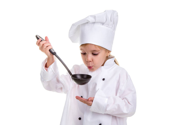 Dziewczyna kucharzem biały uniform izolowana na białym tle. Trzymając czarny kadzi i wieje do niego. Patrząc na kadzi. Obraz pejzaż - Zdjęcie, obraz