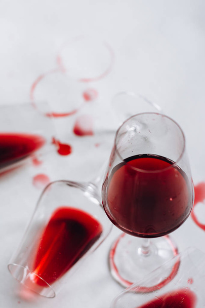 Glasses of spilled red  wine  on white  background,  copy space.  Wine degustation concept - Фото, зображення