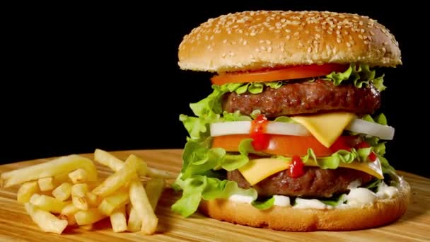 クラフト牛肉のハンバーガーとフライド ポテト黒の背景に分離された木製のテーブルの上. - 映像、動画