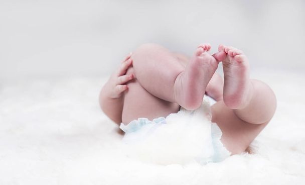 Naked baby legs in a diaper on the beach, close-up. - 写真・画像