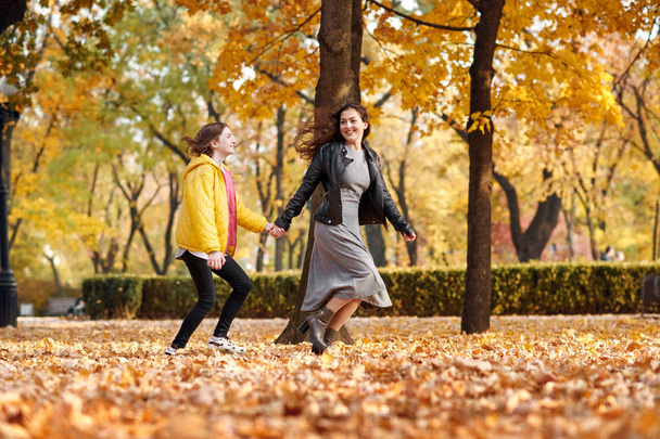 秋の公園で実行されている 2 つの幸せな女の子. - 写真・画像