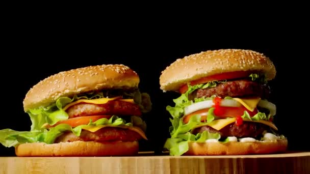 Dvě plavidla hovězí hamburgery na dřevěný stůl izolované na pozadí tmavé odstíny šedi. - Záběry, video