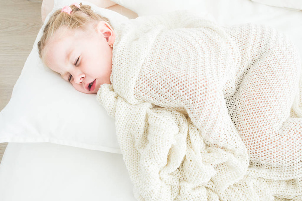Cute little girl sleeping covered in white blanket. - Fotografie, Obrázek