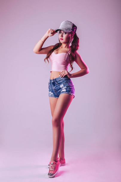 Sexy girl in a cap posing on a lilac background in the studio - Photo, Image