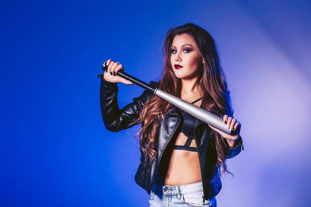 A beautiful girl is holding a baseball bat. Shooting in the studio - Foto, afbeelding