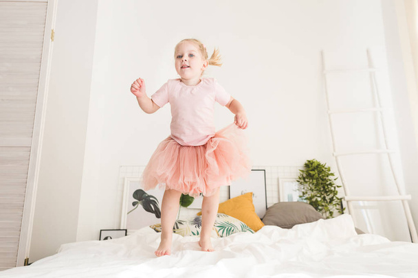 Cute little girl have fun on the bed at home. - 写真・画像