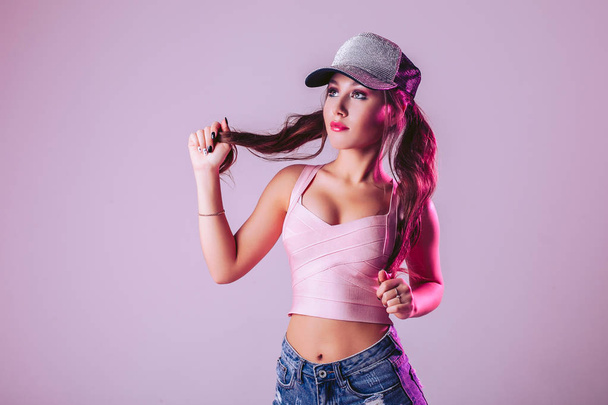 Young woman on a light purple background in the studio, wearing a cap - Fotoğraf, Görsel