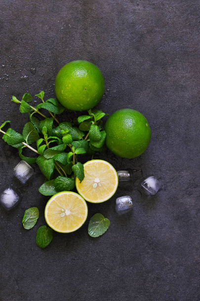 Fresh mint, lime and ice on a black background. Ingredient for mahito. Top view - Valokuva, kuva