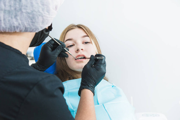 Dental clinic. Reception, examination of the patient. Teeth care. Young girl undergoes a dental examination by a dentist - Φωτογραφία, εικόνα