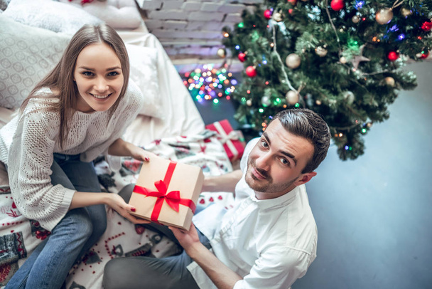 Man give present gift box woman. Christmas holiday. Happy couple sitting on bed. Top View - Foto, Bild