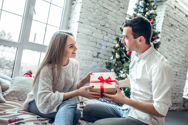 Cute, young couple exchanging Christmas presents on Christmas morning. - Fotografie, Obrázek