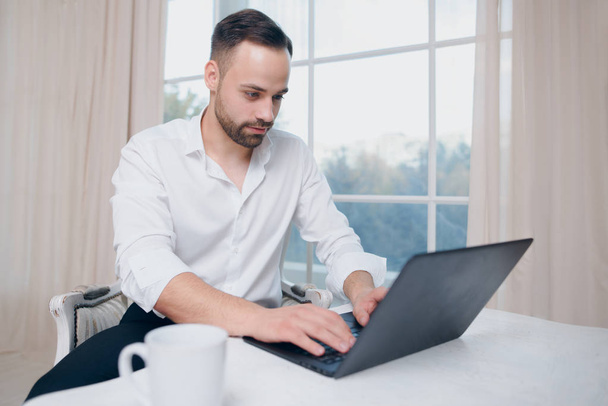 Hipster businessman typing at laptop on window background - Φωτογραφία, εικόνα