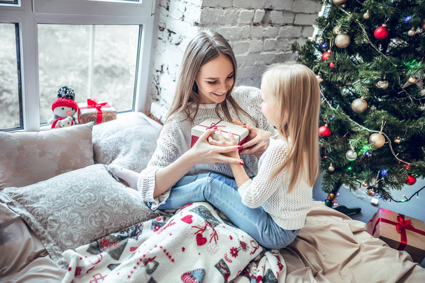 Mother and child at Christmas time. Mom giving baby a gift. New Year and xmas people - Фото, изображение
