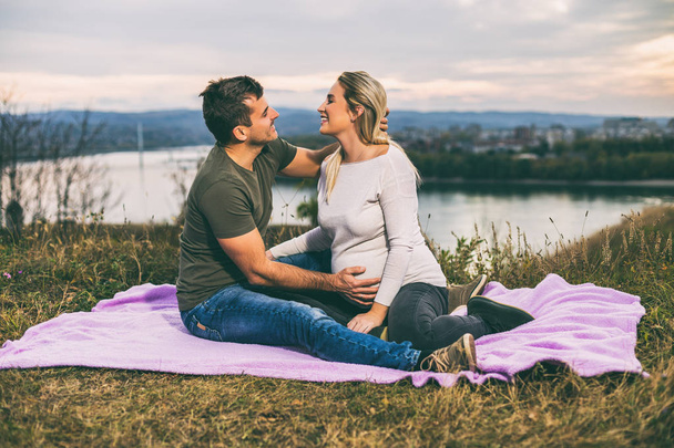 Husband and his pregnant wife enjoy spending time together outdoor.Toned image - Фото, зображення