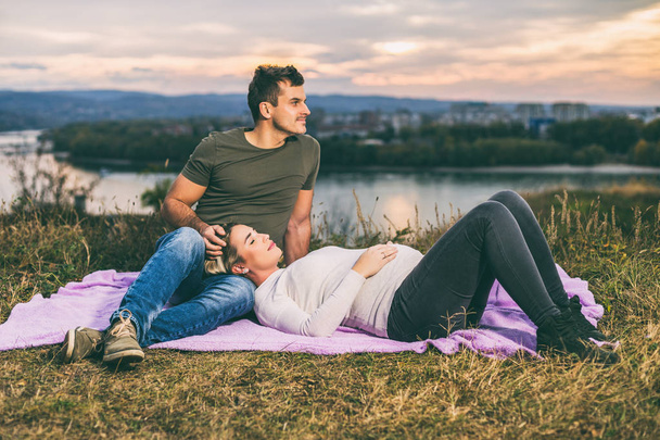 Husband and his pregnant wife enjoy spending time together outdoor.Toned image - Foto, afbeelding