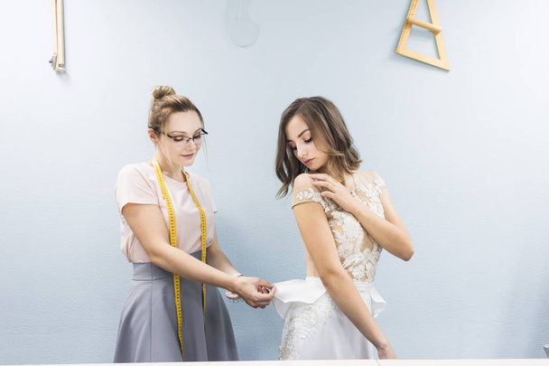 Sewing workshop. Seamstress at work. Seamstress takes measurements of a wedding dress - Foto, Bild