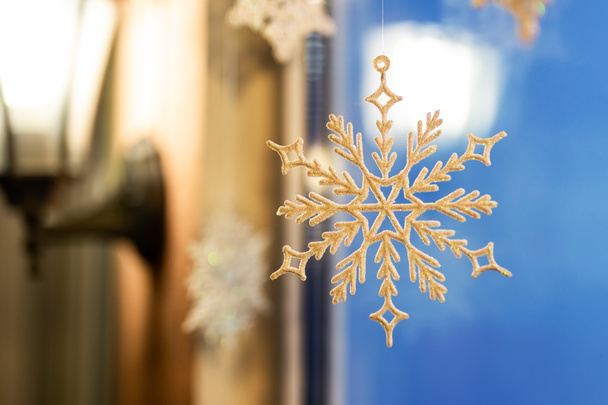 Χριστούγεννα και Πρωτοχρονιά στολίδι διακόσμηση snowlake παρέδωσε κοντά σε παράθυρο με ζεστό λαμπτήρα lattern στο φόντο. Χειμερινές διακοπές σε κάρτα. - Φωτογραφία, εικόνα