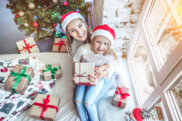 Happy family mother and child girl near a Christmas tree with Christmas present. Top view - Foto, Imagen