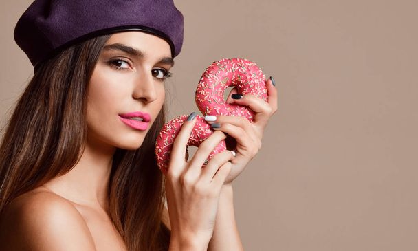 Woman eat sweet pink sugar donuts hungry mouth on light brown background - Φωτογραφία, εικόνα