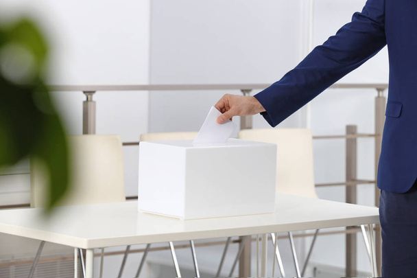Man putting his vote into ballot box at polling station, closeup. Space for text - Foto, Bild