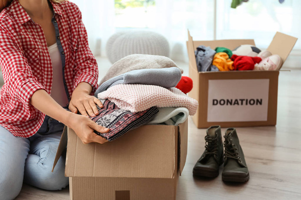 Woman packing clothes into donation box at home - Foto, Bild