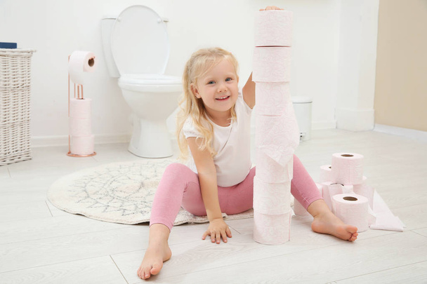 Cute little girl playing with toilet paper in bathroom - Фото, изображение