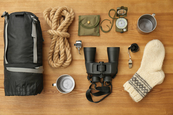Composição de leigos planos com saco de dormir e equipamentos de acampamento em fundo de madeira
 - Foto, Imagem