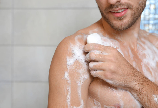 Young man taking shower with soap in bathroom, closeup. Space for text - Fotografie, Obrázek