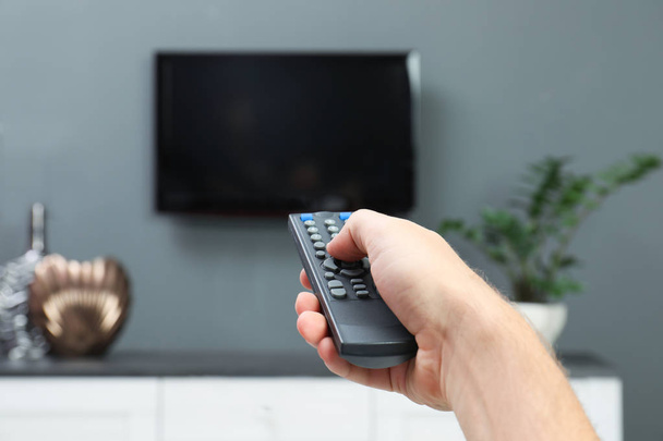 Man switching channels on plasma TV with remote control at home - Foto, Imagem
