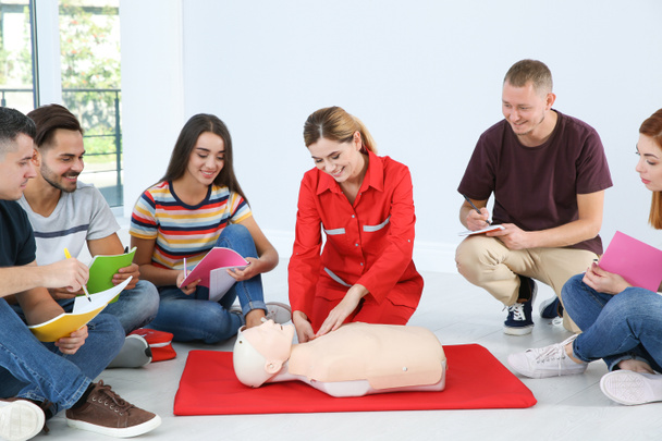 Instructor demonstrating CPR on mannequin at first aid class indoors - Foto, afbeelding