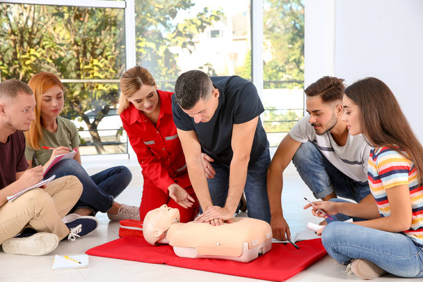 Gruppo di persone con istruttore che praticano CPR sul manichino in classe di primo soccorso al chiuso
 - Foto, immagini
