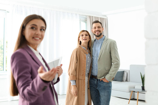 Female real estate agent showing new house to couple, indoors - Foto, immagini