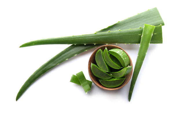 Bowl with pieces of aloe vera and green leaves on white background, top view - Photo, Image