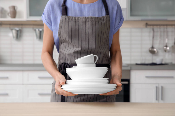 Femme avec vaisselle propre et tasses dans la cuisine, gros plan
 - Photo, image