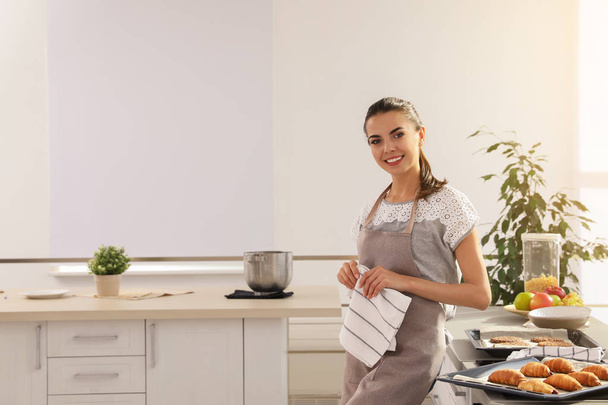 Young woman with homemade oven baked pastry in kitchen, space for text - Foto, Imagem