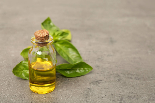 Glass bottle of basil oil with leaves and space for text on table - Foto, Imagen