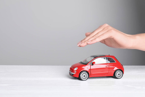 Insurance agent covering toy car on table, closeup. Space for text - Foto, immagini