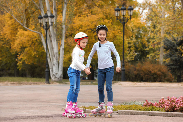 Happy children roller skating in autumn park - Zdjęcie, obraz