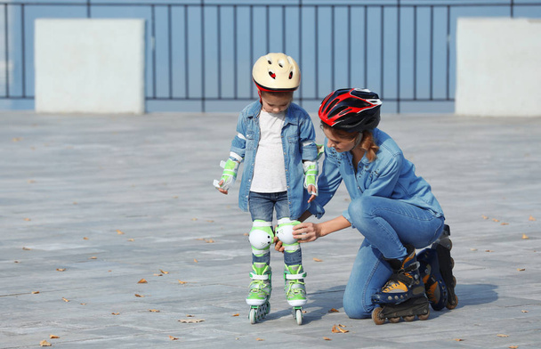 Mother and her daughter wearing roller skates on city street - Zdjęcie, obraz