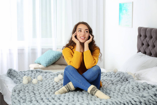 Young beautiful woman in warm sweater on bed at home - Photo, Image