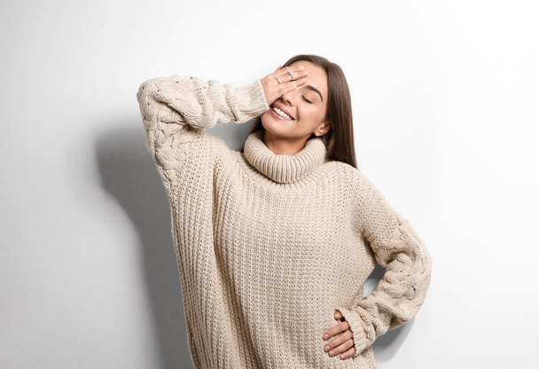 Beautiful young woman in warm sweater on white background - Фото, зображення