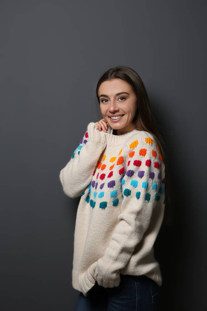 Beautiful young woman in warm sweater on dark background - Fotoğraf, Görsel