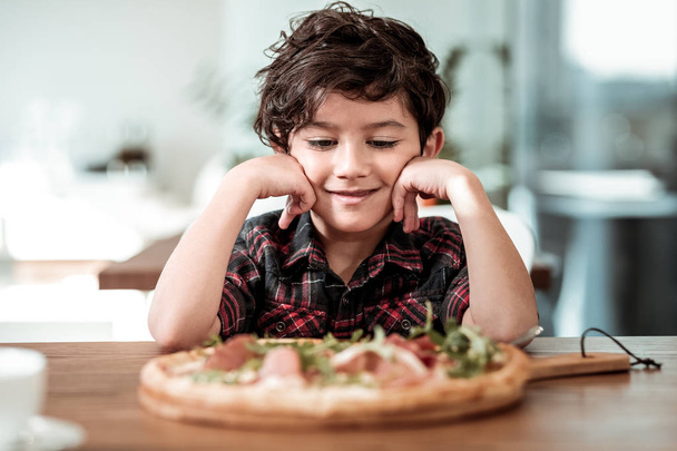 Menino pré-escolar bonito comer pizza com bacon e vegetação no fim de semana
 - Foto, Imagem